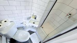 a white bathroom with a shower and a toilet at Stylish 2-Bedroom Flat in Barbican Centre near Farringdon with Rooftop Terrace in London