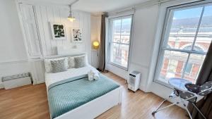 a bedroom with a bed and two large windows at Stylish 2-Bedroom Flat in Barbican Centre near Farringdon with Rooftop Terrace in London