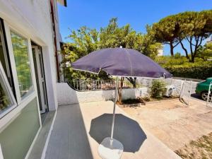 a purple umbrella sitting on the porch of a house at Mono Limone dx con corte, posto auto ed aria condizionata a due passi dal mare in Marcelli