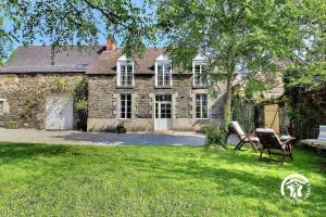 an old stone house with two chairs in the yard at La bretonniere in Taupont