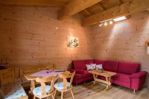 a living room with a red couch and tables at Bauernhof Wildfang in Dalaas