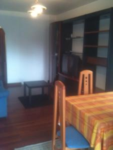 a room with a bed and a tv and a table at Habitaciones López Azcona in Noja