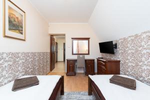 a room with two beds and a desk and a television at Apartament Czarny Potok Lux Zakopane in Zakopane