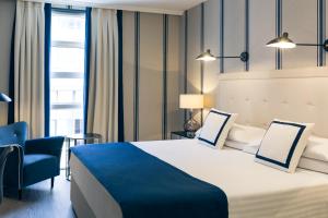 Cette chambre comprend un grand lit et une chaise bleue. dans l'établissement Hotel Mercure Jardines de Albia, à Bilbao