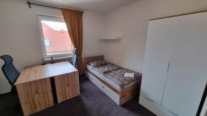a small room with a bed and a desk and a window at Kampus Hotel Poruba in Ostrava