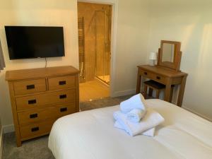 a bedroom with a bed with a dresser and a television at West Beach - Holiday Apartments in Westward Ho