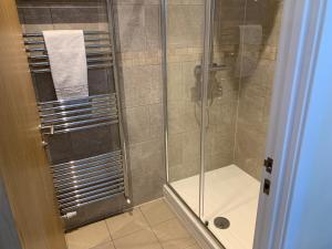 a bathroom with a shower with a glass door at West Beach - Holiday Apartments in Westward Ho