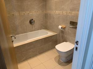 a bathroom with a toilet and a bath tub at West Beach - Holiday Apartments in Westward Ho