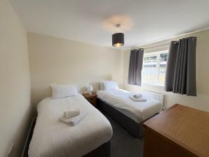 a room with two beds and a window at West Beach - Holiday Apartments in Westward Ho