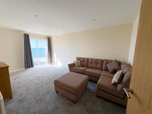 a living room with a couch and a chair and a window at West Beach - Holiday Apartments in Westward Ho