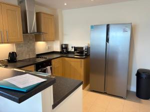 a kitchen with a stainless steel refrigerator and wooden cabinets at West Beach - Holiday Apartments in Westward Ho