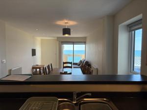 a dining room with a table and chairs and the ocean at West Beach - Holiday Apartments in Westward Ho