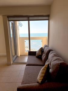 a couch in a room with a view of the beach at West Beach - Holiday Apartments in Westward Ho