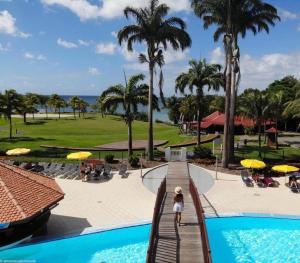 a view of the pool at the resort with palm trees at TI COCOTIER Studio PREMIUM Village Vacances in Sainte-Luce