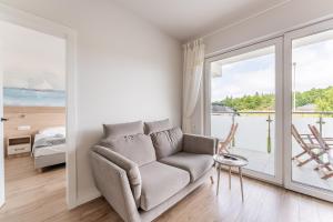 a living room with a couch and a view of the ocean at Sunset Resort VI, Nadmorska 98A in Grzybowo