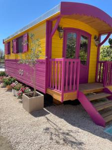 a purple and yellow tiny house with a porch at Aigues Marines in Aigues-Mortes