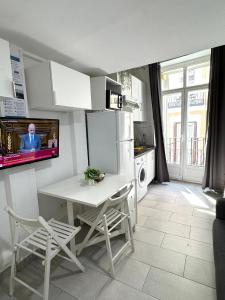 kuchnia ze stołem i telewizorem na ścianie w obiekcie Acogedor apartamento exterior con balcón en el Barrio de Chueca, Gran Vía con aire acondicionado w Madrycie