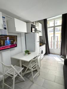 kuchnia ze stołem i białą lodówką w obiekcie Acogedor apartamento exterior con balcón en el Barrio de Chueca, Gran Vía con aire acondicionado w Madrycie