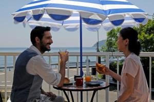 a man and woman sitting at a table under an umbrella at La maison du sud d'awaji - Ocean View Private Villa in Minamiawaji