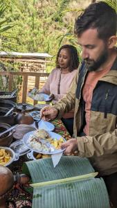 a man sitting at a table with a plate of food at Magamba eco-cultural tourism Farm Stay & Campsite in Lushoto