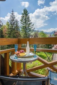 a table with a plate of food and a bottle and glasses at Apartamenty Inny Świat Zakopane in Zakopane