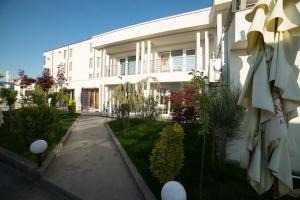 ein weißes Gebäude mit einem Garten davor in der Unterkunft Oneiro Resort in Mamaia Nord – Năvodari