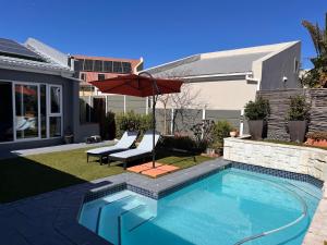 une cour avec une piscine entourée d'un parasol dans l'établissement Family Home in West Beach, Blouberg, au Cap