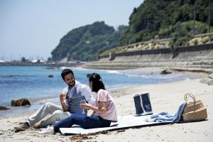 a man and woman sitting on a blanket on the beach at La maison du sud d'awaji - Ocean View Private Villa in Minamiawaji