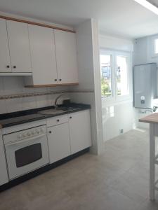 kuchnia z białymi szafkami, zlewem i kuchenką w obiekcie Casa O Vento w mieście O Grove
