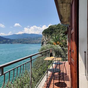 a balcony with a table and chairs next to the water at Peaceful Lakefront in Marone