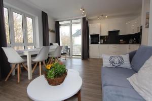 ein Wohnzimmer mit einem blauen Sofa und einem Tisch in der Unterkunft Residenz Düne III - Ferien-Apartments in Boltenhagen in Boltenhagen