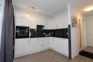 eine weiße Küche mit weißen Schränken und schwarzen Geräten in der Unterkunft Residenz Düne III - Ferien-Apartments in Boltenhagen in Boltenhagen + 22 Fotos