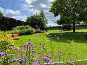 a garden with purple flowers in the grass at Hostellerie du Peiffeschof, The Originals Relais in Arlon