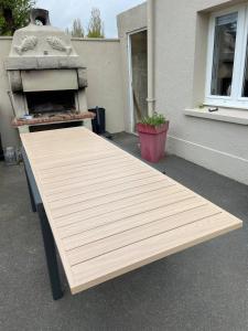 a wooden table sitting in front of a building at La maison du pêcheur ! in Port-Bail-sur-Mer