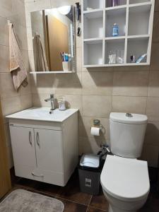 a bathroom with a white toilet and a sink at LS Apartment in Kosovo Polje +6 photos