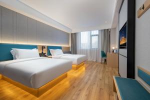 een hotelkamer met twee bedden en een bureau bij Vyluk Hotel Suzhou Xiangcheng Avenue & Global Harbor in Suzhou
