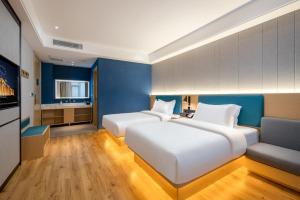 twee bedden in een kamer met blauwe muren bij Vyluk Hotel Suzhou Xiangcheng Avenue & Global Harbor in Suzhou