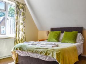 a bedroom with a bed with green pillows and a window at Honey Lodge in Gunnislake +14 photos