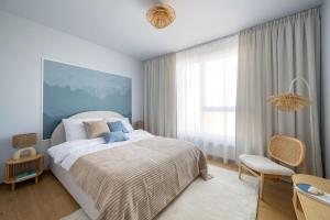 グダニスクにあるElite Apartments Beachside Luxury with Balconyの大きなベッドと椅子のある寝室