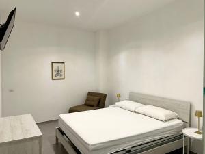 a white bedroom with a bed and a chair at Palazzo Galante in Ginosa Marina