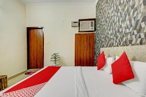 a bedroom with a white bed with red pillows at Hotel O Sky Inn in Ghaziabad +34 photos