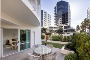 een balkon van een huis met een tafel en stoelen bij Sunny Courtyard Dreaming Downtown with Pool & Gym in Mount Maunganui