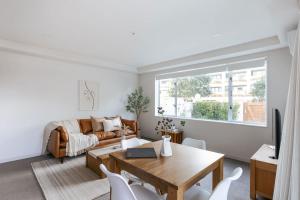 een woonkamer met een tafel en een bank bij Sunny Courtyard Dreaming Downtown with Pool & Gym in Mount Maunganui