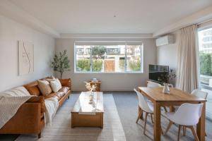 een woonkamer met een bank en een tafel bij Sunny Courtyard Dreaming Downtown with Pool & Gym in Mount Maunganui