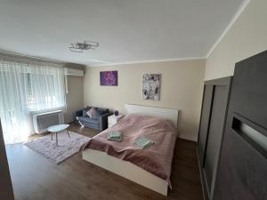 a small bedroom with a bed and a couch at Panoráma Apartman in Makó