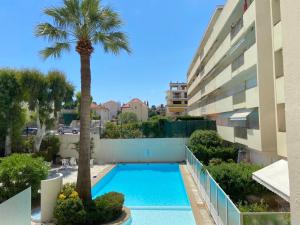 a swimming pool with a palm tree next to a building at Cap d'Antibes Studio et terrasse face à la mer in Antibes