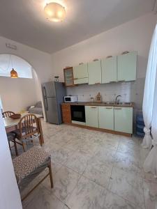 a kitchen with white cabinets and a table and a refrigerator at Green Appartament in Marina di Camerota