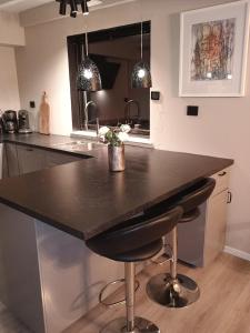 a kitchen with a large black counter with two bar stools at Small farm in Bjørheimsbygd, 30 min from Preikestolen in Strand