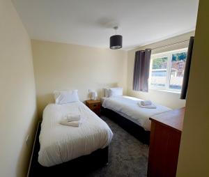 two beds in a small room with a window at West Beach - Holiday Apartments in Westward Ho