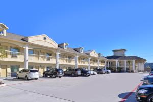 Un gran edificio con coches aparcados en un estacionamiento. en Americas Best Value Inn & Suites - Houston/Hwy 6 & Westpark, en Houston